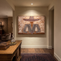 Two Cups Hold the Earth - Rustic Hat Figure with Cups painting by Adrian Lee, mid-century modern horizontal wall art – styled room scene view 3