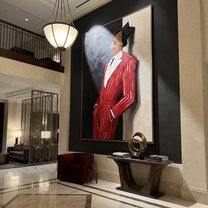 Scarlet Suit Leans into Night - Leaning Red Suit Figure painting by Adrian Lee, mid-century modern vertical wall art – styled room scene view 5