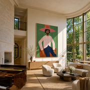 Rose Brim Holds the Green Room - seated pink cowboy painting by Savannah Reed, modern folk art vertical wall art – styled room scene view 1