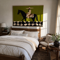 Harlequin Road Carries Her – Olive Cowgirl on Black Horse painting by Isabelle Laurent, modern Western horizontal wall art – styled room scene view 4