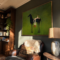 Olive Field Stretches Wide – Black Horse and Red Boots painting by Isabelle Laurent, modern Western horizontal wall art – styled room scene view 4