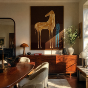 Gold Horse Waits – Golden Horse and Blue Figure painting by Isabelle Laurent, modern Western vertical wall art – styled room scene view 1