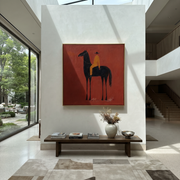 Ochre Stillness Fills the Red Square - black horse rider painting by Isabelle Laurent, modern Western square wall art – styled room scene view 1