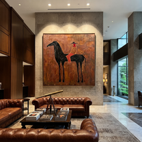Rust Rider Waits on the Black Horse - cowgirl and black horse painting by Isabelle Laurent, modern Western square wall art – styled room scene view 3