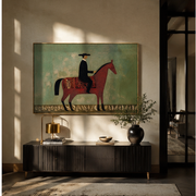 Black Hat Rides the Red Horse through Sage - red horse rider painting by Isabelle Laurent, modern Western horizontal wall art – styled room scene view 1