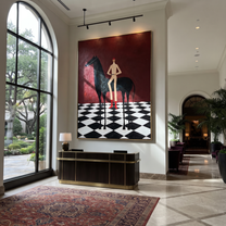 Red Boots Cross Checks - black horse and figure painting by Isabelle Laurent, modern Western vertical wall art – styled room scene view 2