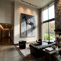 Red Saddle Meets Charcoal - black horse rider painting by Isabelle Laurent, modern Western vertical wall art – styled room scene view 1