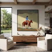 Dusty Trail Carries Home - cowboy trail horse painting by Isabelle Laurent, modern Western square wall art – styled room scene view 1