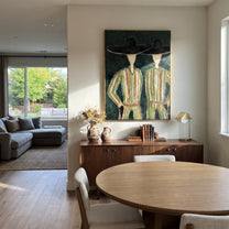 Black Hats Shelter Green - green robe figure pair painting by Elliot Vale, modern figurative vertical wall art – styled room scene view 2