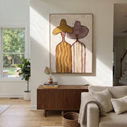 Ochre Hat Meets Mauve - pastel striped figure pair painting by Elliot Vale, modern figurative vertical wall art - styled room scene view 1