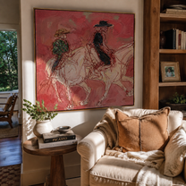 Rose Dust Carries Two Riders - pink horseback pair painting by Ethan Mercer, contemporary western square wall art – styled room scene view 4