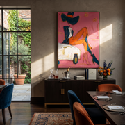 Orange Legs Chase Chrome - cowgirl on car painting by Ethan Mercer, contemporary Western vertical wall art – styled room scene view 1