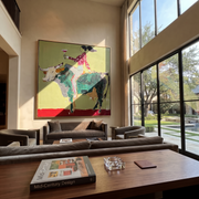 Green Horns Carry Leisure - cowgirl riding bull painting by Ethan Mercer, contemporary Western square wall art – styled room scene view 1