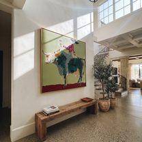 Green Horns Carry Leisure - cowgirl riding bull painting by Ethan Mercer, contemporary Western square wall art – styled room scene view 2