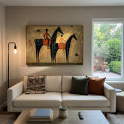Two Riders Cross Ochre - two black horse riders by Ethan Mercer, contemporary Western horizontal wall art – styled room scene view 1