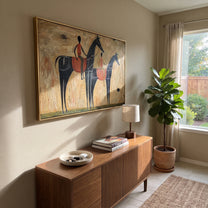 Two Riders Cross Ochre - two black horse riders by Ethan Mercer, contemporary Western horizontal wall art – styled room scene view 2