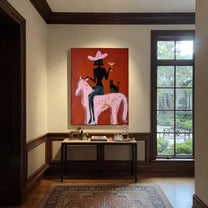 Black Cat Follows Pink - cowgirl pink horse painting by Ethan Mercer, contemporary Western vertical wall art – styled room scene view 1